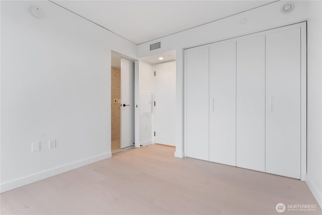 unfurnished bedroom with baseboards, a closet, visible vents, and light wood-style floors