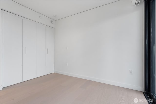 unfurnished bedroom with a closet, light wood-type flooring, and baseboards