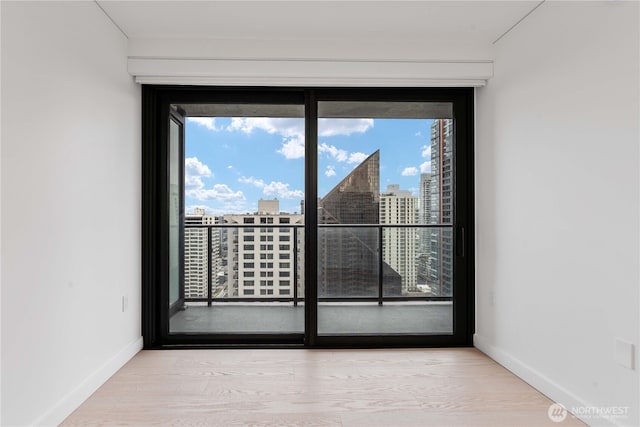 empty room with baseboards, light wood finished floors, and a city view