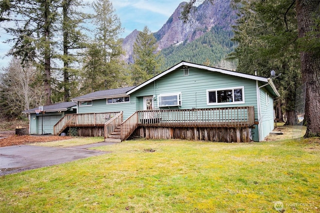 ranch-style house with stairs, a deck with mountain view, and a front yard