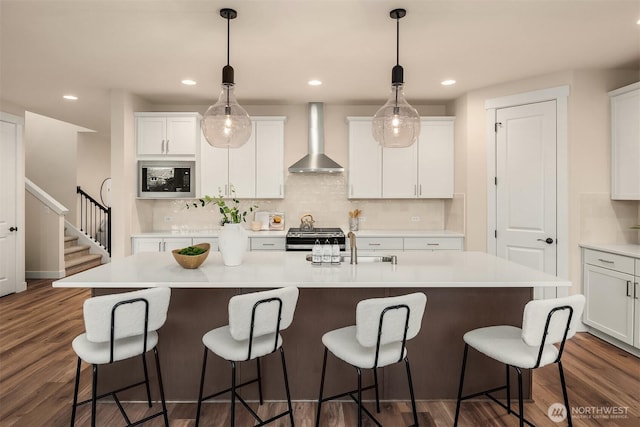 kitchen with white cabinets, dark wood-style floors, stainless steel appliances, wall chimney range hood, and backsplash