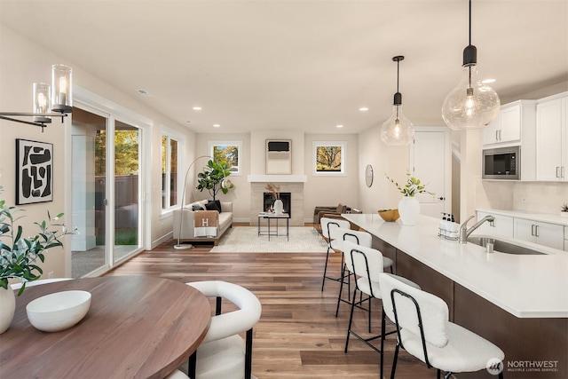 kitchen with a fireplace, light countertops, a sink, wood finished floors, and built in microwave