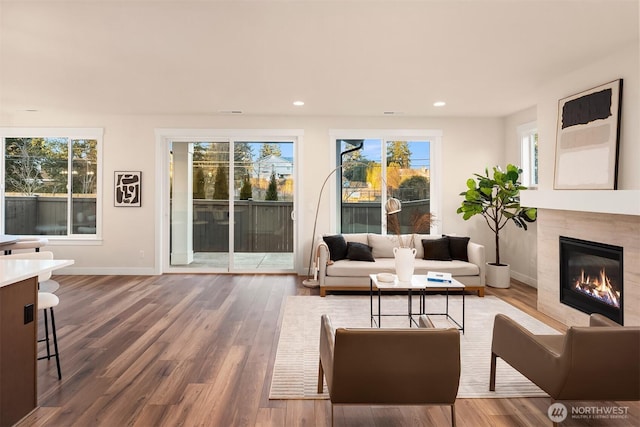 living area with a premium fireplace, recessed lighting, wood finished floors, and a healthy amount of sunlight