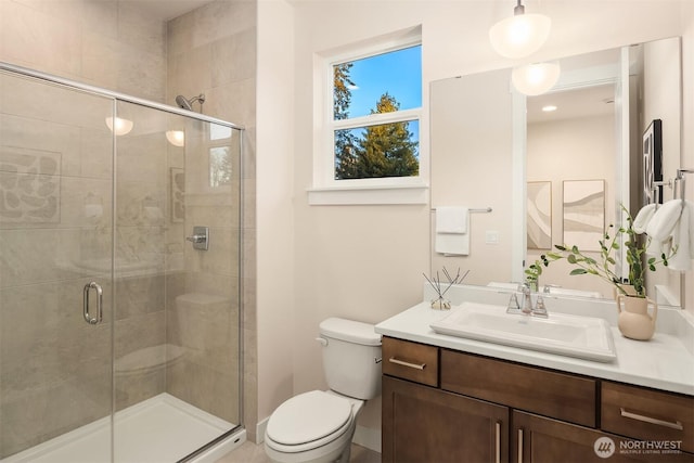 bathroom featuring vanity, a shower stall, and toilet