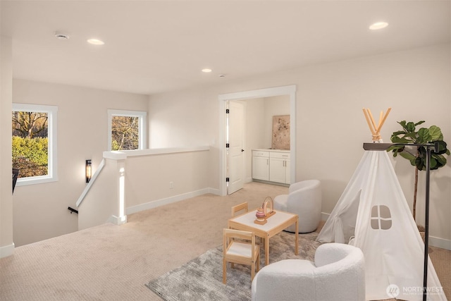 living area with recessed lighting, light carpet, and an upstairs landing