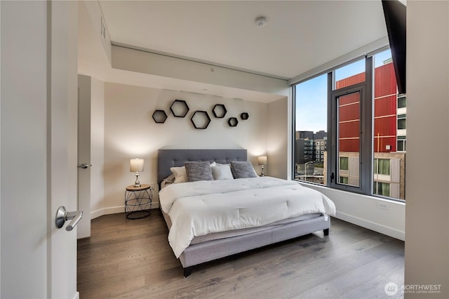 bedroom featuring a view of city, wood finished floors, and baseboards