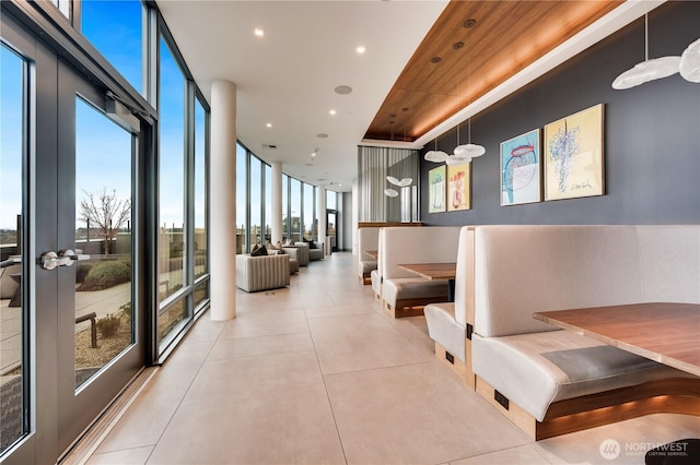 hallway with a wall of windows, recessed lighting, and light tile patterned floors