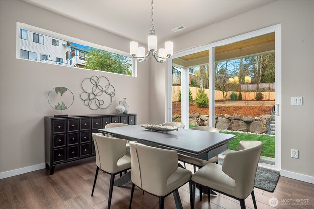 dining area with dark wood-style floors, an inviting chandelier, visible vents, and baseboards