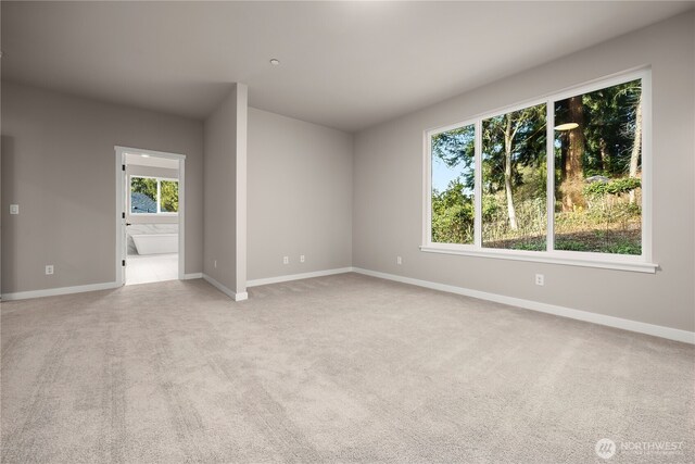 spare room featuring light carpet and baseboards