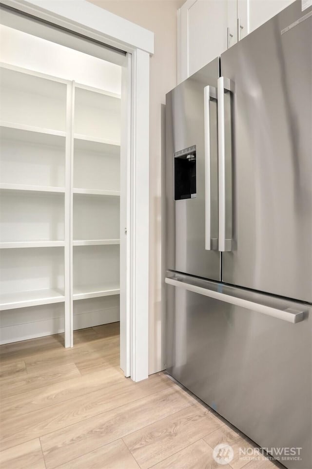 kitchen featuring high end fridge, light wood-type flooring, and white cabinetry