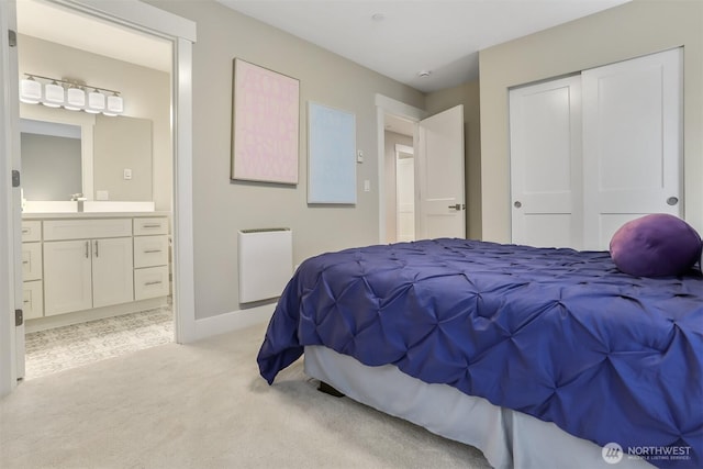 bedroom featuring light colored carpet, ensuite bath, radiator heating unit, a sink, and a closet