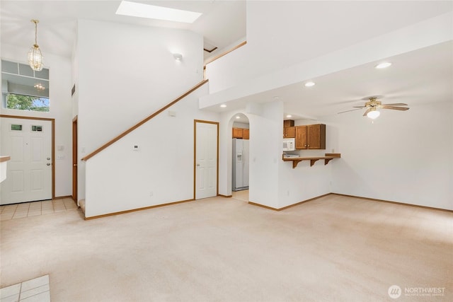 unfurnished living room with high vaulted ceiling, recessed lighting, light colored carpet, and a ceiling fan