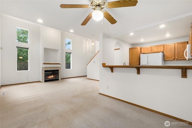 unfurnished living room with recessed lighting, a fireplace, baseboards, and light colored carpet