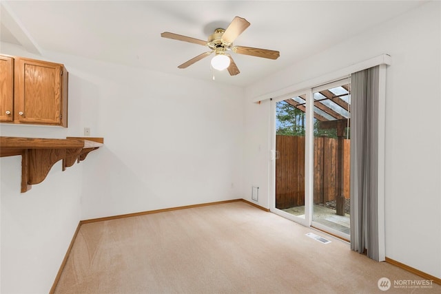spare room with light carpet, a ceiling fan, visible vents, and baseboards