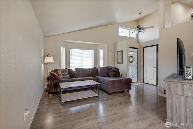 living area with dark wood-type flooring, plenty of natural light, a ceiling fan, and baseboards