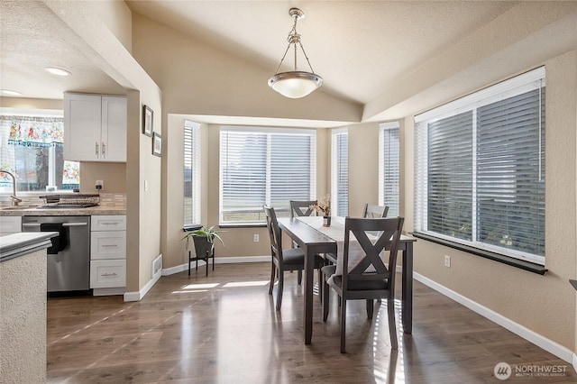 dining space featuring dark wood-type flooring, visible vents, vaulted ceiling, and baseboards