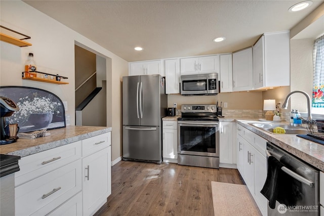 kitchen featuring a sink, white cabinetry, light wood-style floors, light countertops, and appliances with stainless steel finishes