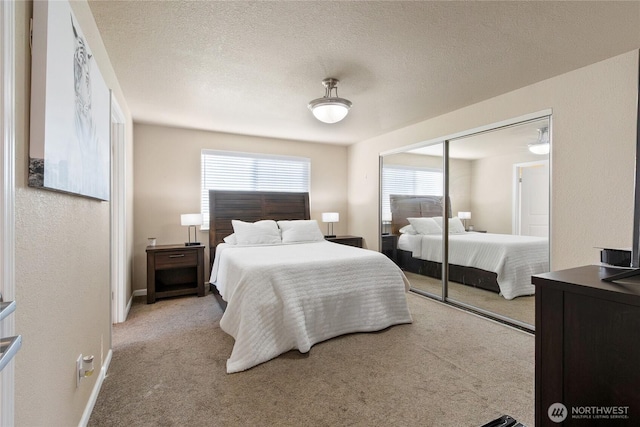 bedroom featuring light carpet, a textured ceiling, a closet, and baseboards