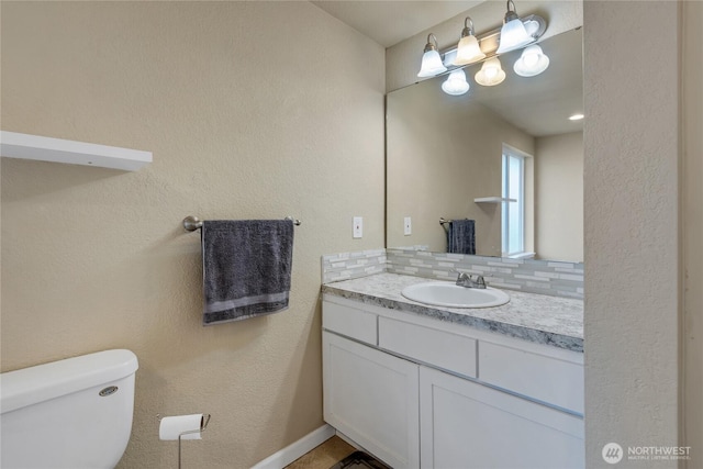 bathroom with backsplash, vanity, and toilet