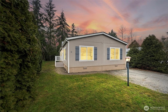 view of front of house with driveway, crawl space, and a lawn