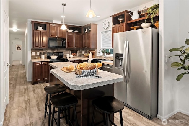 kitchen featuring decorative backsplash, hanging light fixtures, light countertops, black appliances, and open shelves