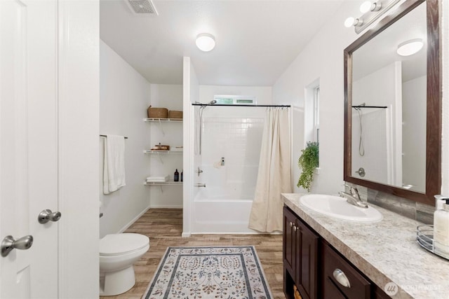 full bathroom featuring toilet, wood finished floors, visible vents, vanity, and shower / tub combo with curtain