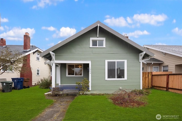 rear view of house featuring fence and a yard