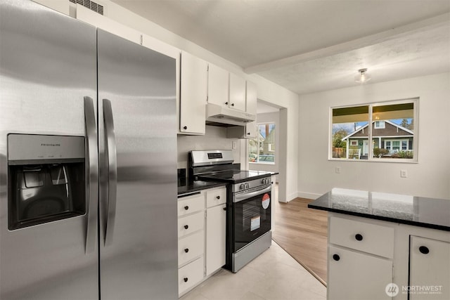 kitchen with light tile patterned floors, appliances with stainless steel finishes, white cabinetry, dark stone counters, and under cabinet range hood