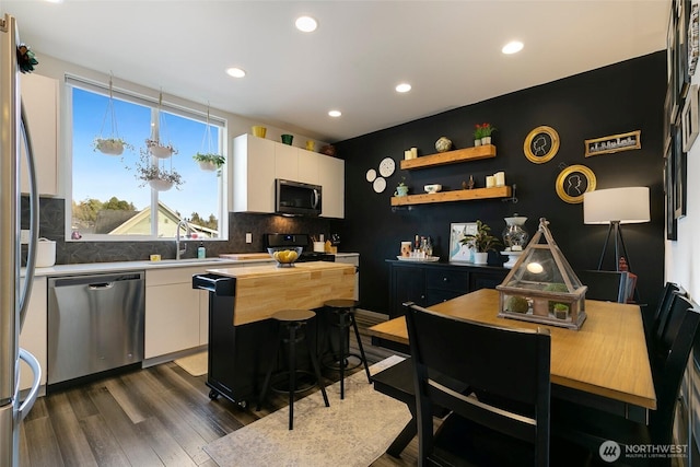 kitchen featuring stainless steel appliances, dark wood-type flooring, white cabinetry, a center island, and open shelves