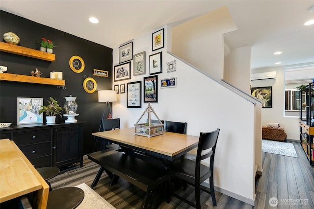 dining room with an AC wall unit, dark wood-style flooring, recessed lighting, and baseboards