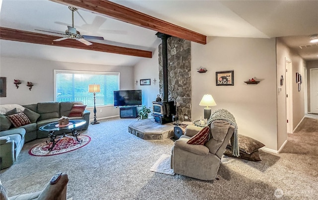 carpeted living area featuring lofted ceiling with beams, baseboards, a wood stove, and a ceiling fan