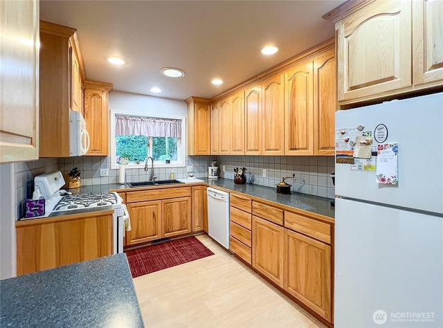 kitchen with white appliances, tasteful backsplash, dark countertops, light wood-type flooring, and a sink