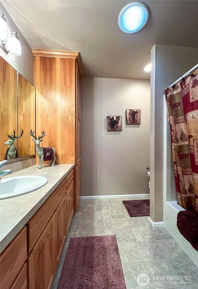 bathroom featuring tile patterned flooring, shower / tub combo with curtain, vanity, and baseboards