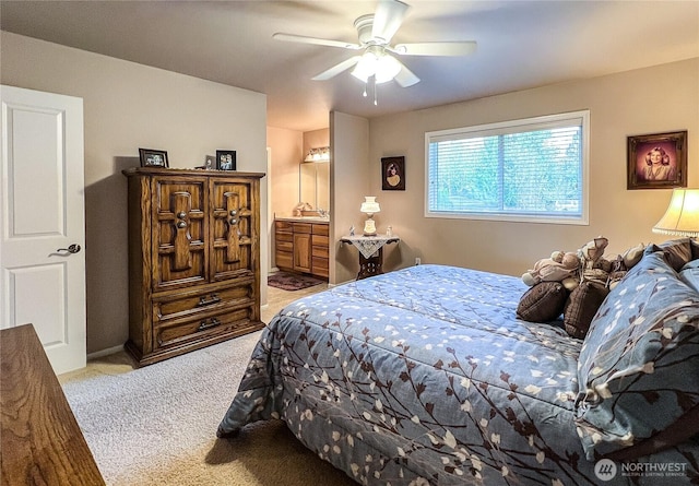 bedroom featuring a ceiling fan, light colored carpet, and connected bathroom