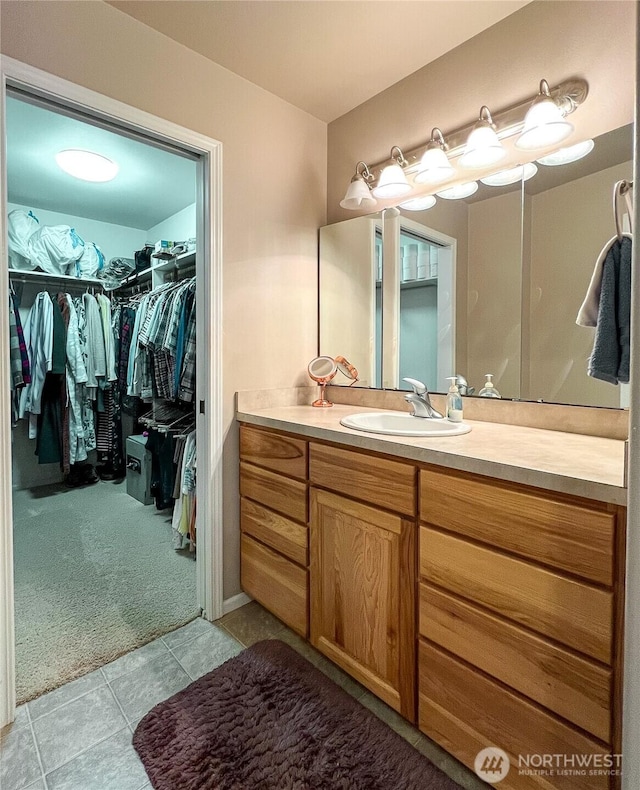 bathroom with a spacious closet, tile patterned flooring, and vanity