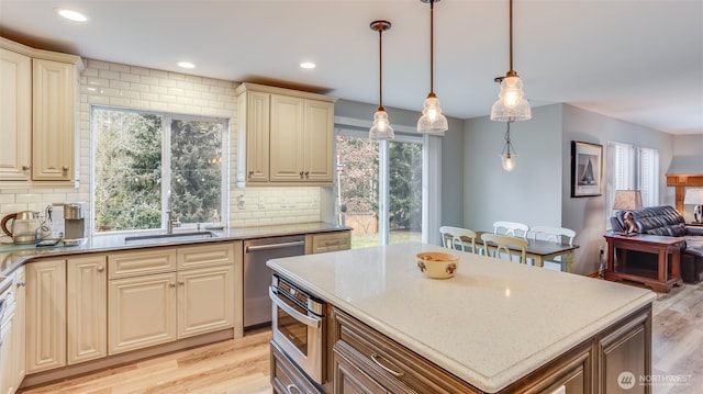 kitchen featuring decorative light fixtures, a sink, light wood-style flooring, and cream cabinets