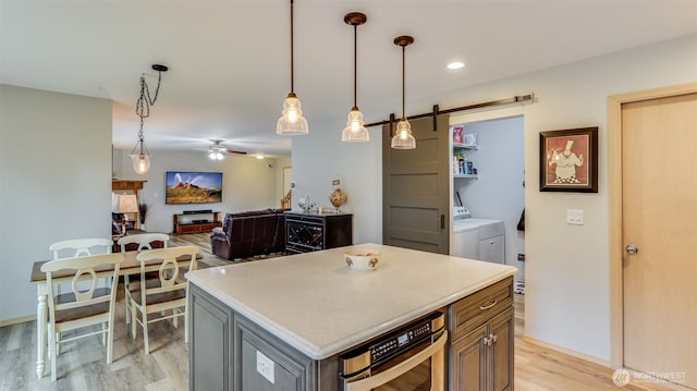 kitchen featuring gray cabinetry, a kitchen island, open floor plan, hanging light fixtures, and washing machine and clothes dryer