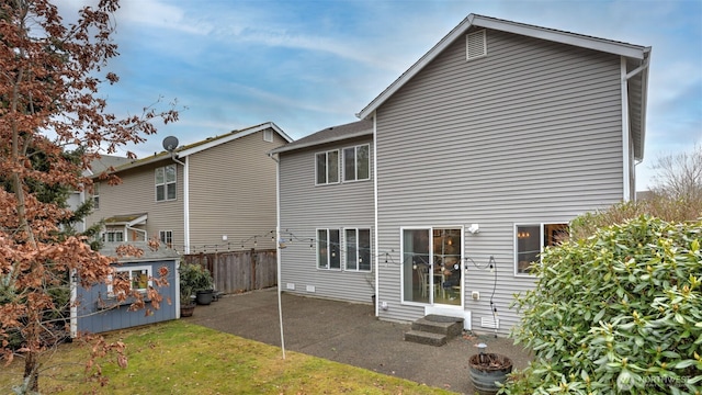 rear view of house with entry steps, a patio, and fence