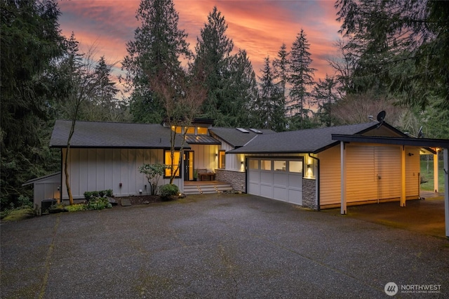 view of front facade with stone siding, board and batten siding, an attached garage, and driveway