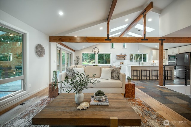 living area featuring a skylight, recessed lighting, visible vents, wood finished floors, and beamed ceiling