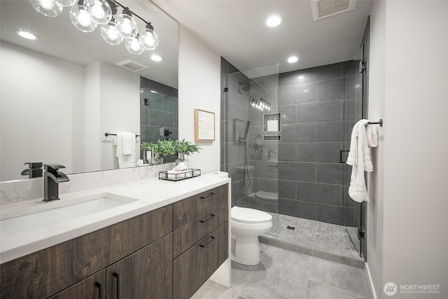 bathroom featuring visible vents, vanity, toilet, and tiled shower