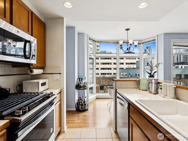 kitchen with stainless steel appliances, light countertops, and decorative light fixtures