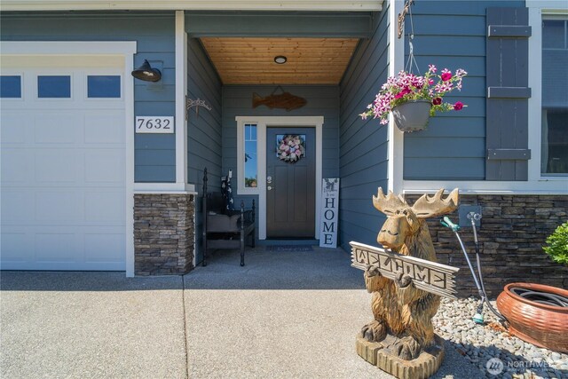 entrance to property with stone siding and an attached garage