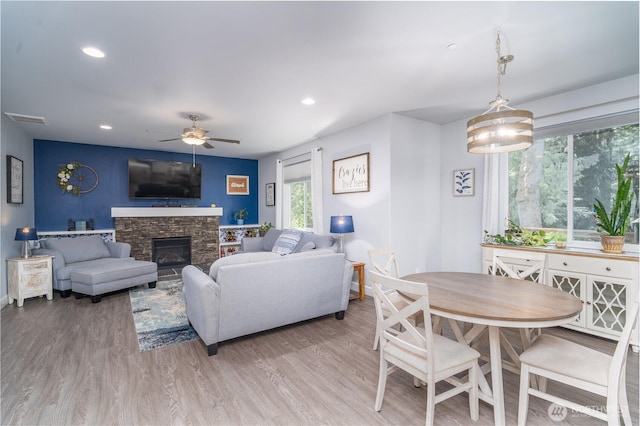 living area featuring recessed lighting, visible vents, a stone fireplace, and wood finished floors