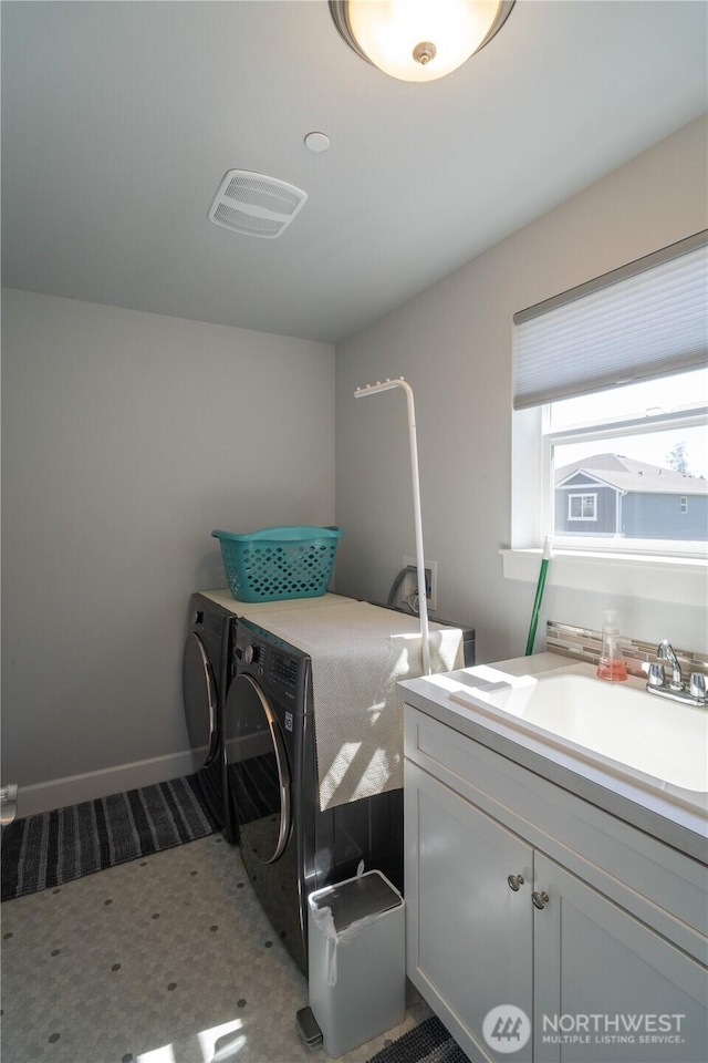 washroom with cabinet space, baseboards, visible vents, washer and clothes dryer, and a sink