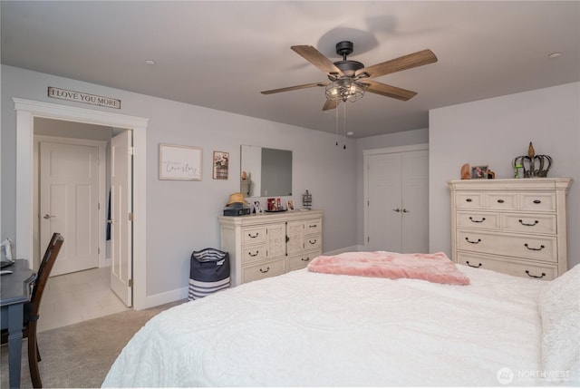 bedroom featuring light carpet, ceiling fan, baseboards, and a closet