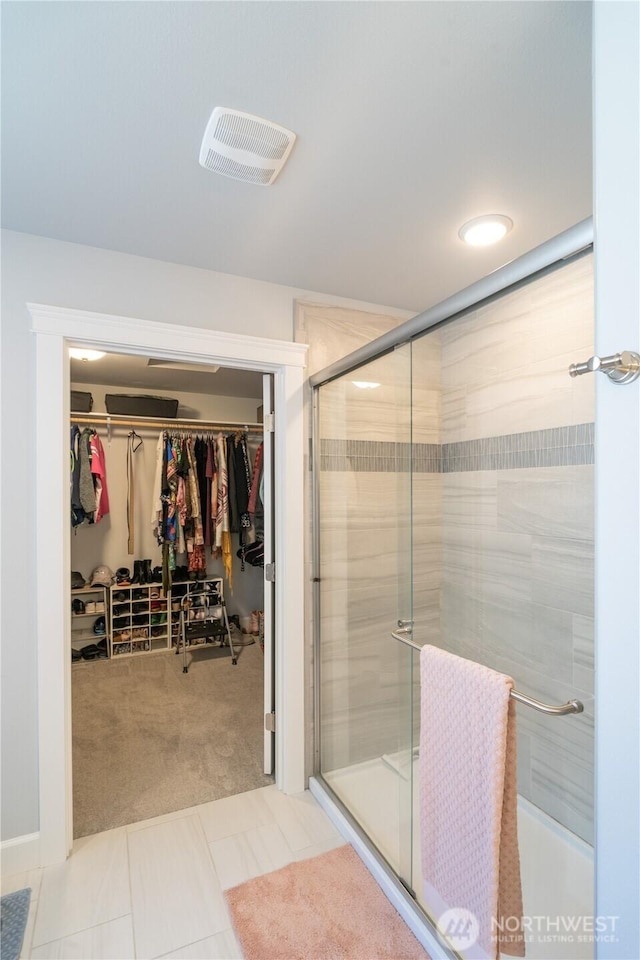 full bathroom featuring a stall shower, a walk in closet, tile patterned flooring, and visible vents