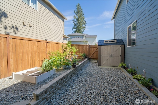 view of yard featuring a storage shed, a garden, a fenced backyard, and an outdoor structure