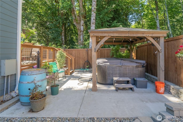 view of patio with a hot tub, a fenced backyard, and a gazebo