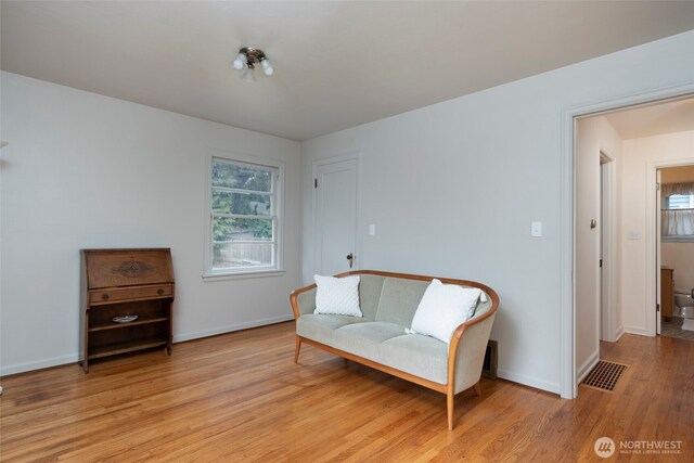 sitting room with light wood finished floors, baseboards, and visible vents